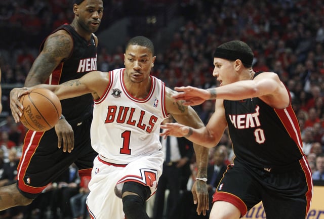 Chicago Bulls' Derrick Rose (C) is guarded by Miami Heat's Mike Bibby and LeBron James (L) during Game 1 of their NBA Eastern Conference Finals playoff basketball game in Chicago May 15, 2011. REUTERS/Jeff Haynes/File Photo