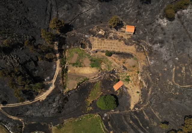 A drone view shows structures surrounded by scorched land in the aftermath of a wildfire in Unhais da Serra, Covilha area, Portugal, August 21, 2025. REUTERS/Violeta Santos Moura