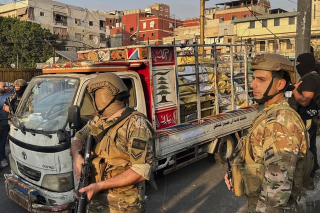 Army soldiers stand next to a pickup carrying weapons handed over by Palestinian factions at the Burj al-Barajneh Palestinian refugee camp in Beirut, Lebanon, Thursday, Aug. 21, 2025, in an initial step to implement a plan officials announced three months earlier for removing arms from the camps. (AP Photo/Hussein Malla)