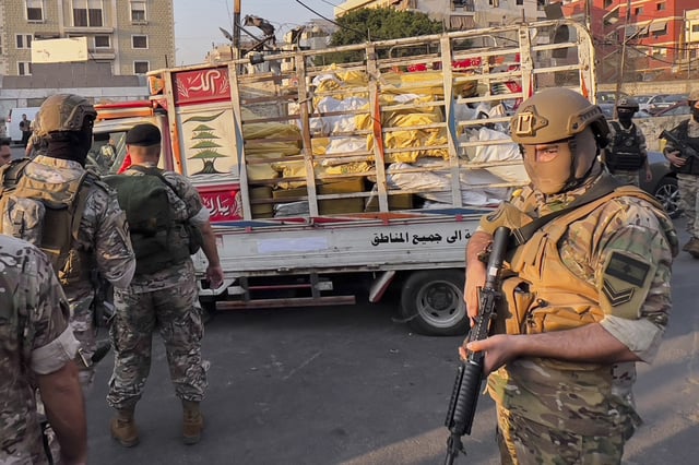 Army soldiers stand next to a pickup carrying weapons handed over by Palestinian factions at the Burj al-Barajneh Palestinian refugee camp in Beirut, Lebanon, Thursday, Aug. 21, 2025, in an initial step to implement a plan officials announced three months earlier for removing arms from the camps. (AP Photo/Hussein Malla)