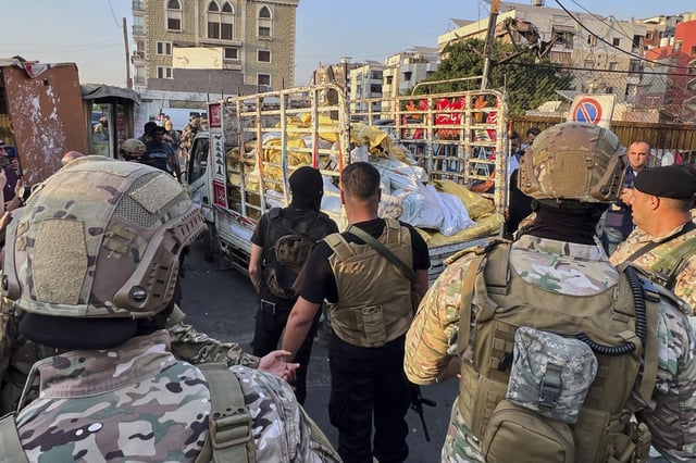 Army soldiers stand next to a pickup carrying weapons handed over by Palestinian factions at the Burj al-Barajneh Palestinian refugee camp in Beirut, Lebanon, Thursday, Aug. 21, 2025, in an initial step to implement a plan officials announced three months earlier for removing arms from the camps. (AP Photo/Hussein Malla)