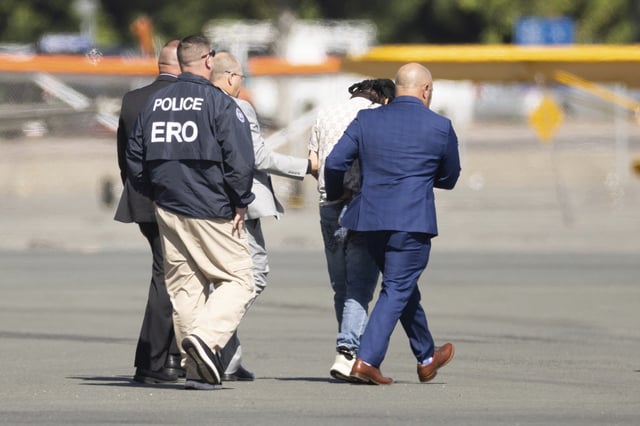 Harjinder Singh is escorted to an airplane by Florida Lt. Gov. Jay Collins and law enforcement on Thursday, Aug. 21, 2025, in Stockton, Calif. (AP Photo/Benjamin Fanjoy)
