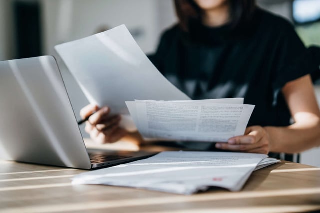A young woman looks over pages of bills