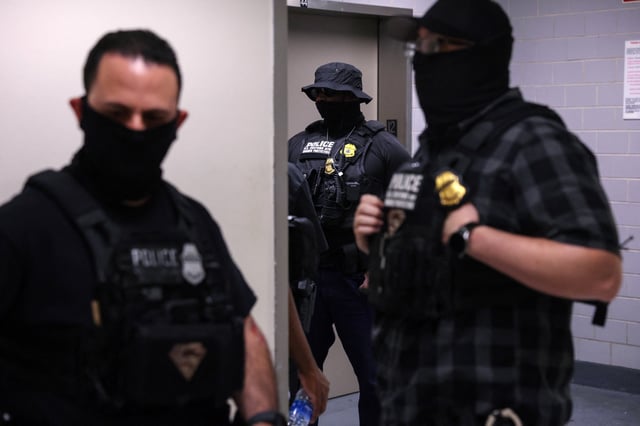 Federal immigration officers stand with masks, as federal detainments continue, in the hallways of U.S. immigration court in New York City, U.S., August 19, 2025. REUTERS/Shannon Stapleton/File photo