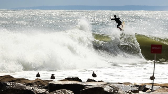 A surfer rides a high wave due to the effects of Hurricane Erin in the Rockaway Beach neighborhood in Queens 