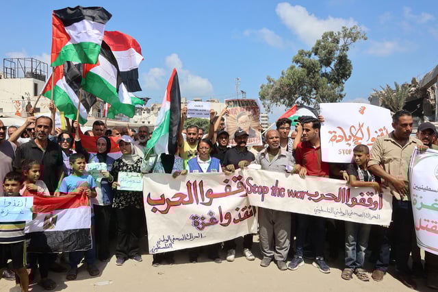 Palestinians wave their national flag and chant slogans in Gaza City on August 21, 2025, during a demonstration to call for an end to the more than 22 months of war between Hamas and Israel. Israel hammered Gaza City and its outskirts overnight, residents said on August 20, as the military announced it had taken initial steps in its push to capture Hamas's last major stronghold. (Photo by Omar AL-QATTAA / AFP) (Photo by OMAR AL-QATTAA/AFP via Getty Images)          