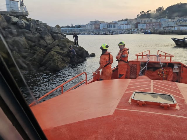 Un momento del rescate del marinero en el espigón del muelle de Cangas.
