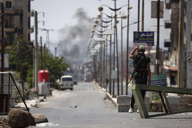 A Druze militiaman at a check point looks a smoke in the background following last week's sectarian clashes in the Druze-majority town of Sweida, Syria, Friday, July 25, 2025. (AP Photo/Omar Sanadiki)
