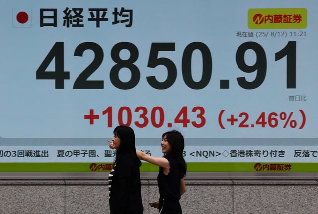 Pedestrians walk past a stock quotation board showing the Nikkei share average outside a brokerage in Tokyo, Japan, August 12, 2025. REUTERS/Kim Kyung-Hoon/File Photo