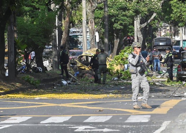 Members of the security forces and people work next to debris following the explosion of a cargo vehicle near an Aerospace Force base, in one of two attacks attributed to FARC dissident groups, that caused multiple casualties, according to authorities, in Cali, Colombia August 21, 2025. REUTERS/Oswaldo Paez