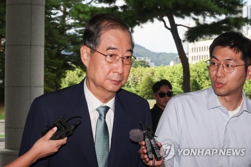 Former Prime Minister Han Duck-soo (L) arrives at special counsel Cho Eun-suk's office in southern Seoul on Aug. 22, 2025, to undergo questioning over his alleged involvement in former President Yoon Suk Yeol's martial law declaration. (Yonhap)