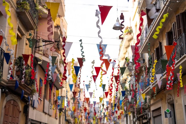 Vecinos y vecinas del barrio de Sants ultiman los detalles de la decoración en una de las calles engalanadas para la Festa Major 2025.