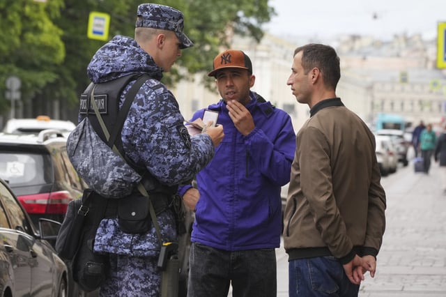 FILE - A Russian National Guard serviceman checks residency documents during a raid outside the Apraksin Dvor clothing market, in St. Petersburg, Russia, Friday, July 4, 2025. (AP Photo/File)