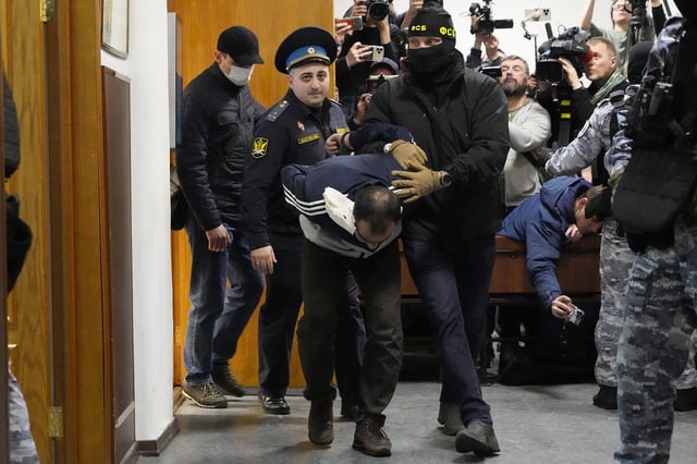 FILE - Saidakrami Murodali Rachabalizoda, a Tajik national who was arrested after the shooting and arson attack at a concert, is escorted by police and FSB officers in the Basmanny District Court in Moscow, Russia, March 24, 2024. (AP Photo/Alexander Zemlianichenko, File)