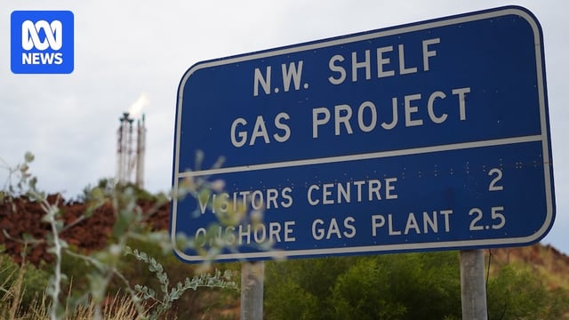 A blue sign reading 'N.W. Shelf Gas Project' with flare tower spitting flames in the background.