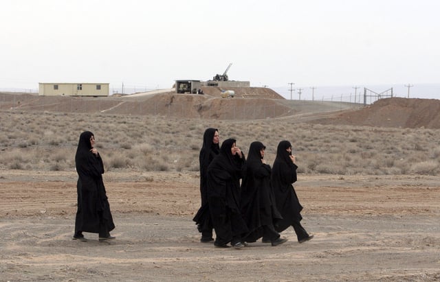 FILE - Iranian women walk past an anti-aircraft gun, at the conclusion of a rally to support Iran's nuclear programs, in front of the Natanz Uranium Enrichment Facility, some 200 miles (322 km) south of the capital Tehran, Iran, March 9, 2006. (AP Photo/Vahid Salemi, File)