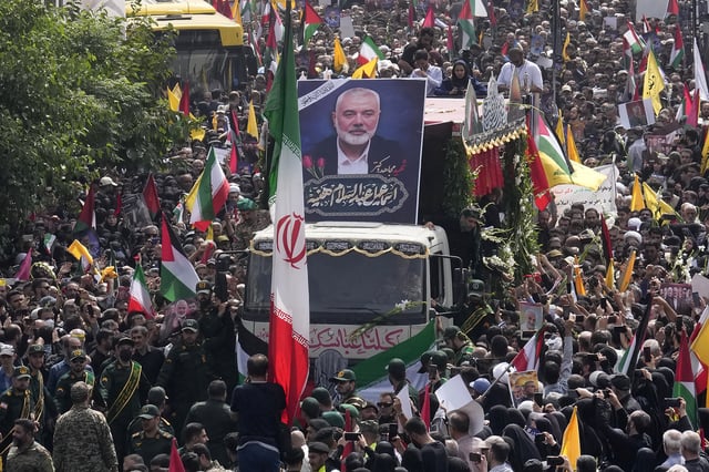 FILE- Iranians follow a truck, center, carrying the coffins of Hamas leader Ismail Haniyeh and his bodyguard who were killed in an assassination blamed on Israel on Wednesday, during their funeral ceremony at Enqelab-e-Eslami (Islamic Revolution) Sq. in Tehran, Iran, Aug. 1, 2024. (AP Photo/Vahid Salemi, file)