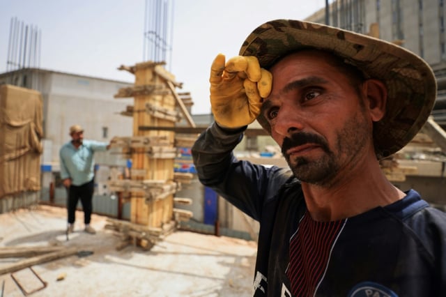 Un ouvrier qui travaille sur un chantier de construction essuie la sueur de son front alors que les températures augmentent avec l'arrivée de l'été à Bagdad, le 28 mai 2025