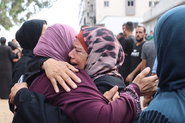 Palestinians mourn relatives, killed in Israeli strikes, ahead of their funeral at Al-Shifa hospital in Gaza City on Aug. 21.