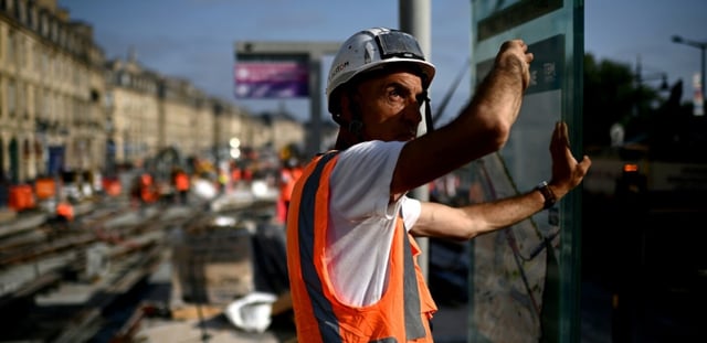 Un ouvrier qui travaille sur un chantier de lignes de tramway le long de la Garonne se protège du soleil pendant une vague de chaleur à Bordeaux, dans le sud-ouest de la France, le 1er juillet 2025