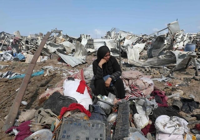 Una mujer palestina desplazada se sienta con sus pertenencias tras un ataque israelí contra un campamento para desplazados internos en Deir el-Balah, en el centro de la Franja de Gaza