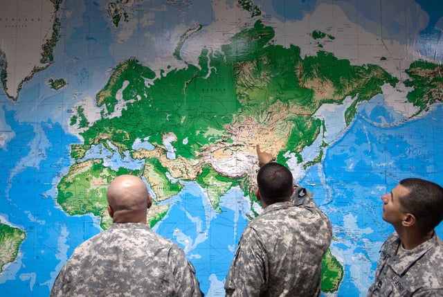 FILE - Soldiers look at a world map as they wait to board a flight in Manas, Kyrgyzstan, on the way home after completing a deployment in Afghanistan, Thursday, Aug. 11, 2011. (AP Photo/David Goldman, file)