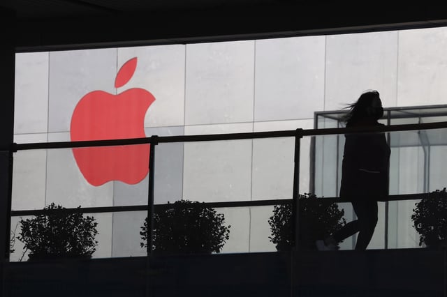 A woman runs past an Apple logo in Beijing, Dec. 6, 2018 (AP photo by Ng Han Guan).