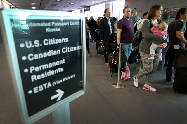 Stock photograph showing passengers waiting in line to use the Automated Passport Control Kiosks set up for international travellers arriving at Miami International Airport on March 4, 2015 in Miami, Florida.