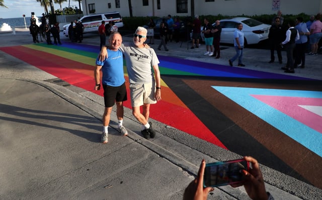 Joey Lachimia and Richard Arsenault, of Fort Lauderdale, take pictures in front of the first rainbow crosswalk in Broward County, on Sebastian Street in Fort Lauderdale on Monday, Nov. 15, 2021. The crosswalk is a temporary sticker unveiled before the Pride Fort Lauderdale festival Saturday and Sunday on the beach. The permanent crosswalk will be painted at a later date.