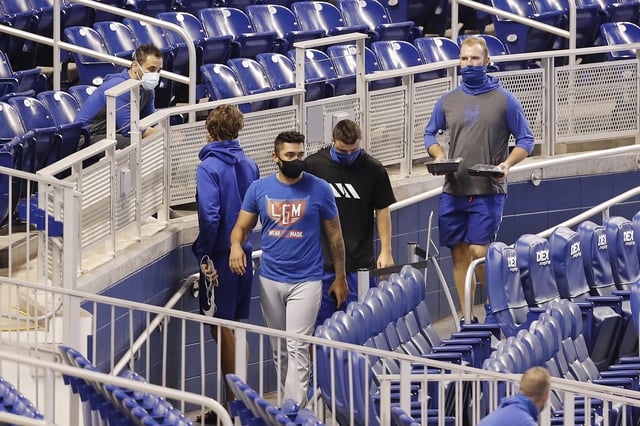 Pete Alonso #20 and Ali Sanchez #70 of the New York Mets walk to the clubhouse after the game between the New York Mets and the Miami Marlins was postponed due to a member of the Mets organization testing positive for COVID-19 at Marlins Park on August 20, 2020 in Miami, Florida.