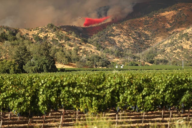 A plane drops fire retardant as the Pickett Fire burns near Calistoga, forcing evacuations at several wineries on Thursday, Aug. 21, 2025.
