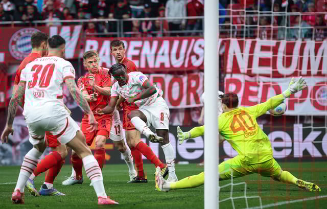 Bayern Munich's German goalkeeper #40 Jonas Urbig (R) saves a shot by Leipzig's Malian midfielder #08 Amadou Haidara during the German first division Bundesliga football match between RB Leipzig and FC Bayern Munich in Leipzig, eastern Germany on May 3, 2025.