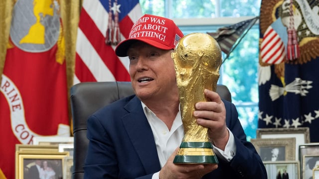 US President Donald Trump holds the World Cup trophy in the Oval Office of the White House in Washington, DC, on August 22, 2025. Trump announced the 2026 World Cup draw will be held on December 5 at Washington's Kennedy Center. (Photo by ANDREW CABALLERO-REYNOLDS / AFP)