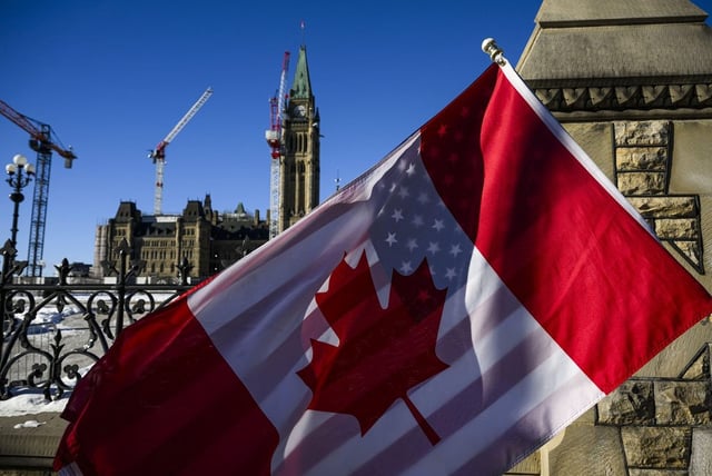 A protester holds the flags of Canada and the United States outside on Parliament Hill in Ottawa, on Saturday, Feb. 1, 2025. THE CANADIAN PRESS/Justin Tang