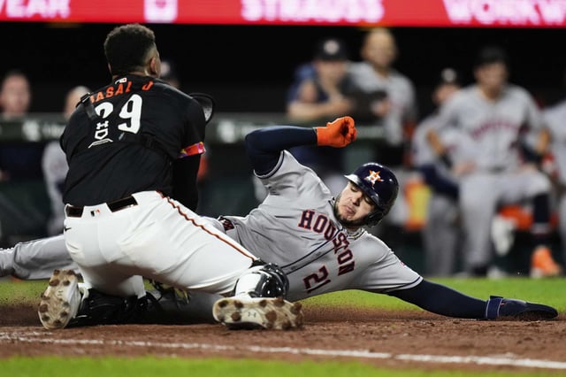 Houston Astros' Yainer Diaz (21) is tagged out at home plate by Baltimore Orioles catcher Sam Basallo, left, during the eighth inning of a baseball game, Friday, Aug. 22, 2025, in Baltimore.