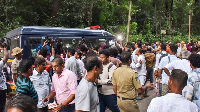 People gather near a site of an alleged burial related to the Dharmasthala mass burial case, at Dharmasthala, in Dakshina Kannada district.