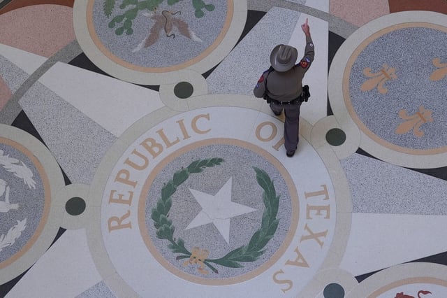 A Texas troopers passes the Texas Seal in the Rotunda of the Texas Capitol before debate on a bill on a redrawn U.S. congressional map during a special session in the Senate Chamber in Austin, Texas, Friday, Aug. 22, 2025. (AP Photo/Eric Gay)