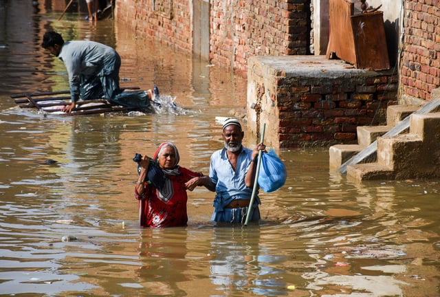 People wade through a flooded street after the rain at Latifabad, Hyderabad, Pakistan, August 22, 2025. REUTERS/Yasir Rajput