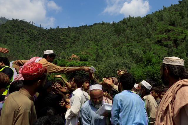 Residents gather to receive the food handouts, following a storm that caused heavy rains and flooding in Qadir Nagar area, in Buner district, Khyber Pakhtunkhwa province, Pakistan, August 21 2025. REUTERS/Akhtar Soomro