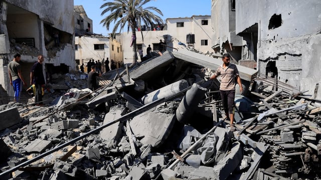 Palestinians inspect the site of an Israeli strike on a house in Deir Al-Balah, in the central Gaza Strip