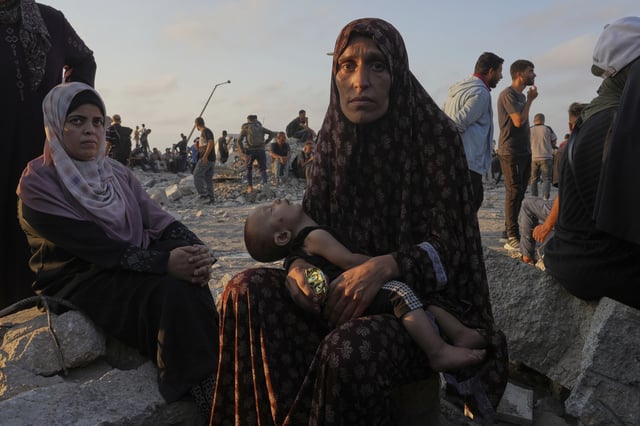 Somoud Wahdan looks at the camera while she and her child wait for trucks of humanitarian aid to arrive in Gaza City, July 25, 2025. (AP Photo/Abdel Kareem Hana)