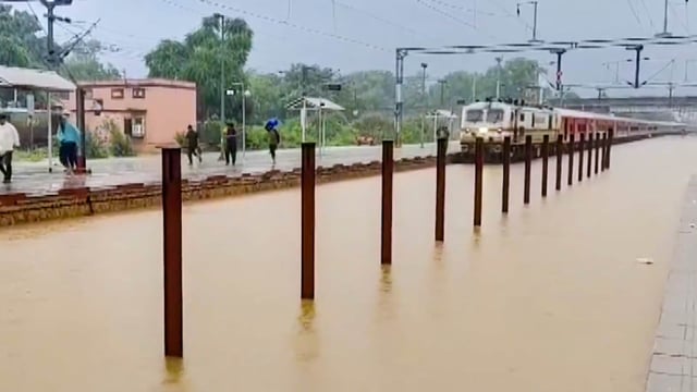 A train passes on railway tracks submerged in floodwater due to heavy rainfall, at a station, in Sawai Madhopur, Rajasthan, Friday, Aug. 22, 2025