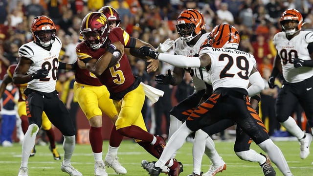 Aug 18, 2025; Landover, Maryland, USA; Washington Commanders quarterback Jayden Daniels (5) runs with the ball past Cincinnati Bengals defensive tackle Howard Cross III (95) and Bengals cornerback Cam Taylor-Britt (29) to score a touchdown during the first quarter at Northwest Stadium. Mandatory Credit: Geoff Burke-Imagn Images