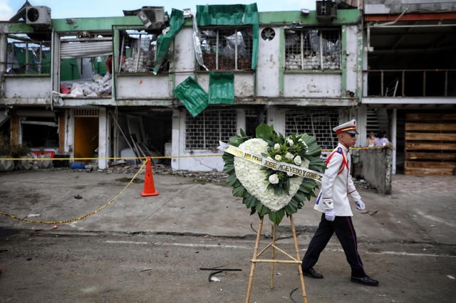Un estudiante de escuela militar camina el viernes 22 de agosto de 2025 tras colocar un arreglo de flores en honor de las personas que fallecieron en la víspera por un atentado perpetrado afuera de una base de la Fuerza Aérea en Cali, Colombia. (AP Foto/Santiago Saldarriaga)