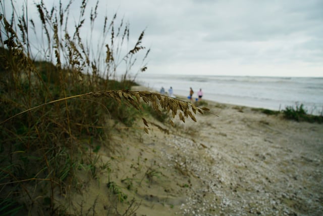 People walk on Coquina Beach near Oregon Inlet, N.C., which cremains closed because of damage from Hurricane Erin on Friday, Aug. 22, 2025. (AP Photo/Allen G. Breed)