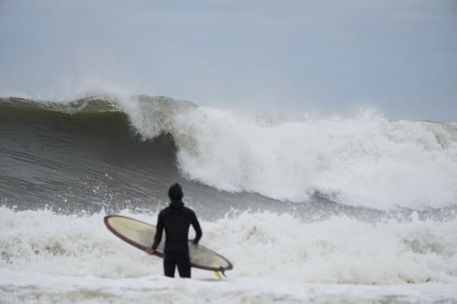 A surfer tries to get in the water, past big waves bolstered by Hurricane Erin, at Rockaway Beach in the Queens borough of New York, Thursday, Aug. 21, 2025. (AP Photo/Seth Wenig)