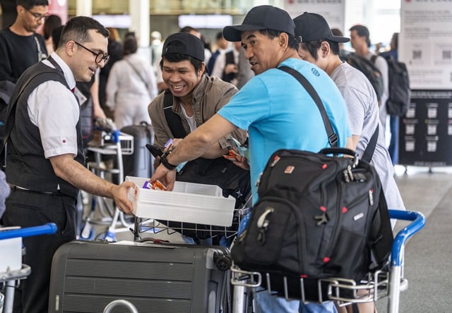 An Air Canada employee hands out snacks to travellers waiting for a flight at Montreal-Pierre Elliott Trudeau International Airport in Dorval, Que., on Tuesday, Aug. 19, 2025. THE CANADIAN PRESS/Christinne Muschi