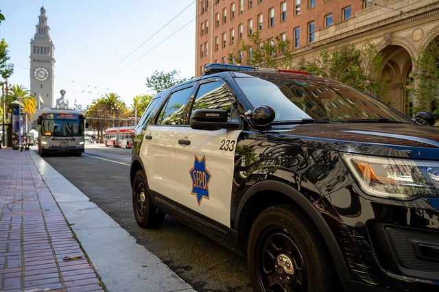 A San Francisco Police Department SUV parked on Market Street with the Ferry Building clock tower and Muni buses in the background, San Francisco, May 20, 2025.