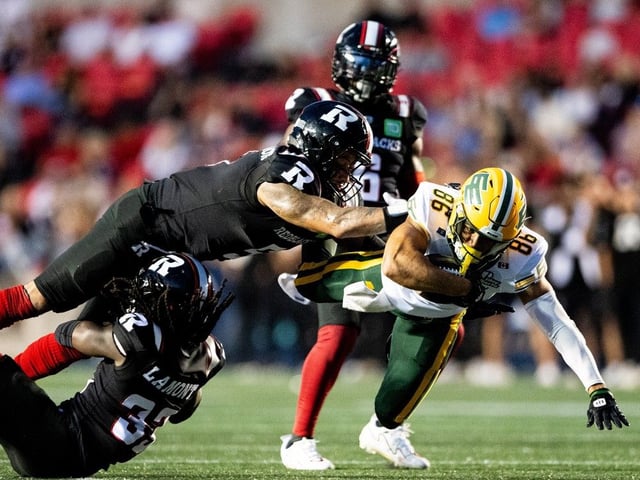 Edmonton Elks wide receiver Arkell Smith (86) is tackled by Ottawa Redblacks linebacker Jovan Santos-Knox (5) during first half of regular season CFL action in Ottawa, on Friday, Aug. 22, 2025.