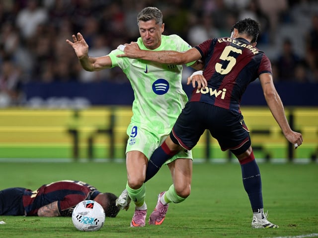 Soccer Football - LaLiga - Levante v FC Barcelona - Esatdio Ciudad de Valencia, Valencia, Spain - August 23, 2025 FC Barcelona's Robert Lewandowski in action with Levante's Unai Elgezabal REUTERS/Pablo Morano